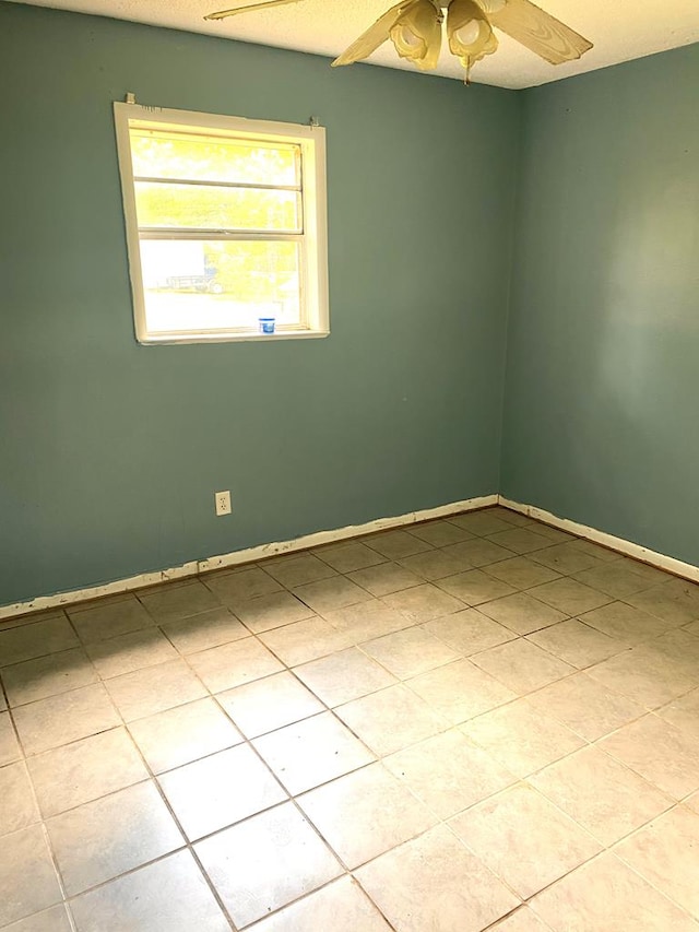 unfurnished room with tile patterned floors, ceiling fan, and baseboards