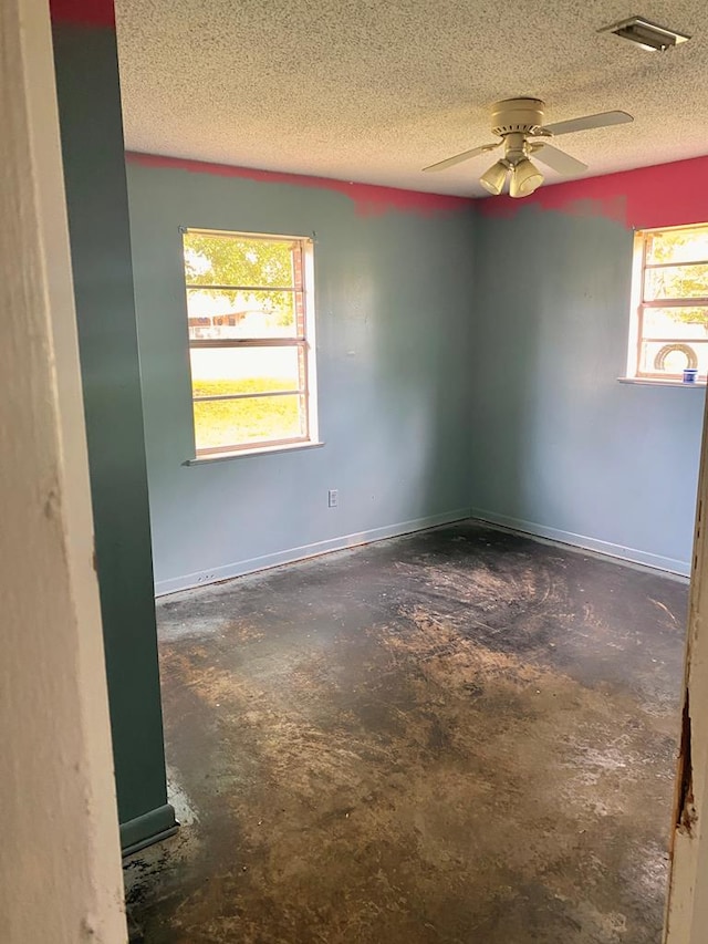 empty room with visible vents, ceiling fan, a textured ceiling, and concrete floors