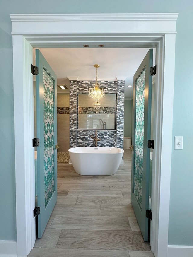 bathroom with a bathing tub, a notable chandelier, and hardwood / wood-style floors