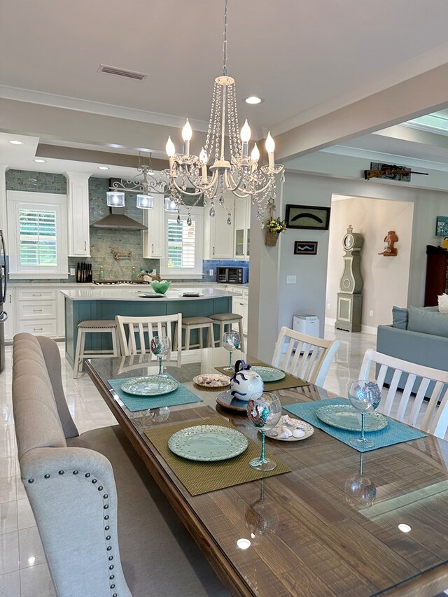 tiled dining space with plenty of natural light, ornamental molding, and a chandelier