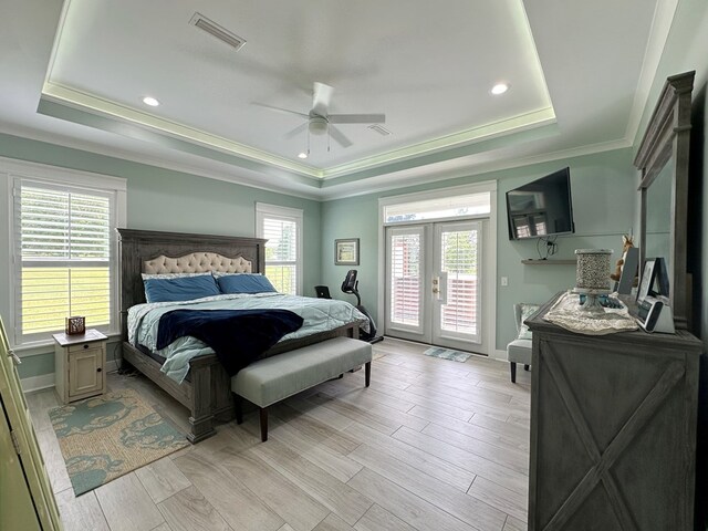 bedroom with a raised ceiling, french doors, and multiple windows