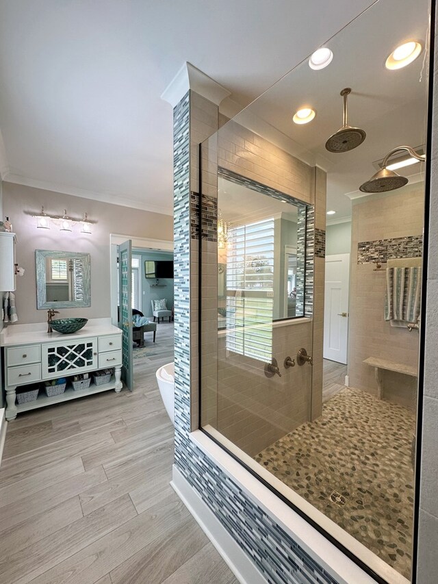 bathroom with a shower, hardwood / wood-style floors, vanity, and ornamental molding