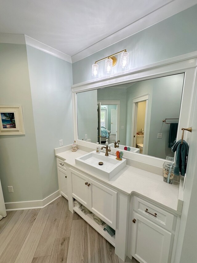 bathroom with hardwood / wood-style floors, vanity, and ornamental molding