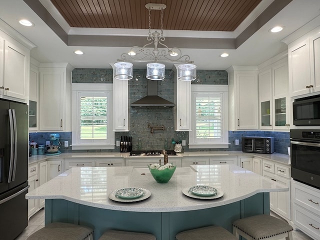 kitchen featuring a breakfast bar area, a raised ceiling, plenty of natural light, and stainless steel appliances