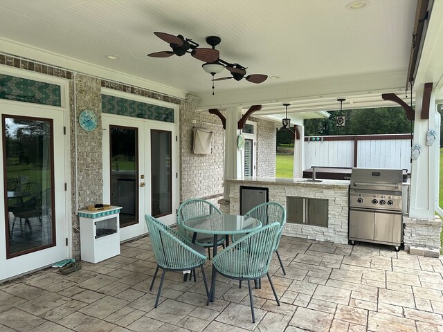 view of patio featuring exterior bar, grilling area, ceiling fan, and exterior kitchen