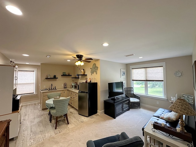 living room with light hardwood / wood-style floors, ceiling fan, and sink