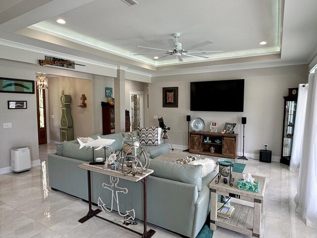 living room with ceiling fan, ornamental molding, and a tray ceiling