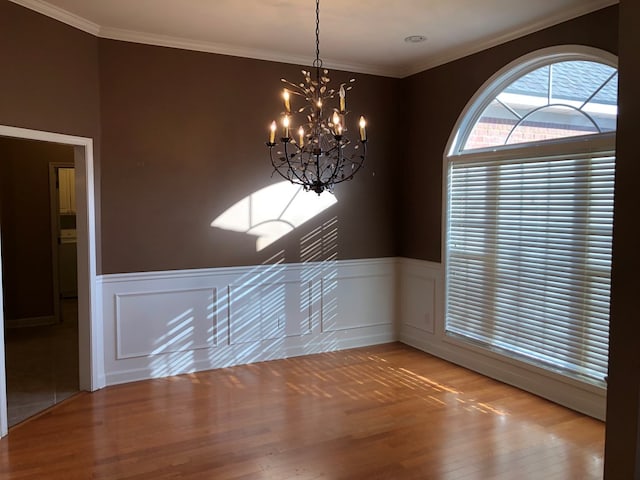 unfurnished dining area featuring crown molding, hardwood / wood-style floors, and a chandelier