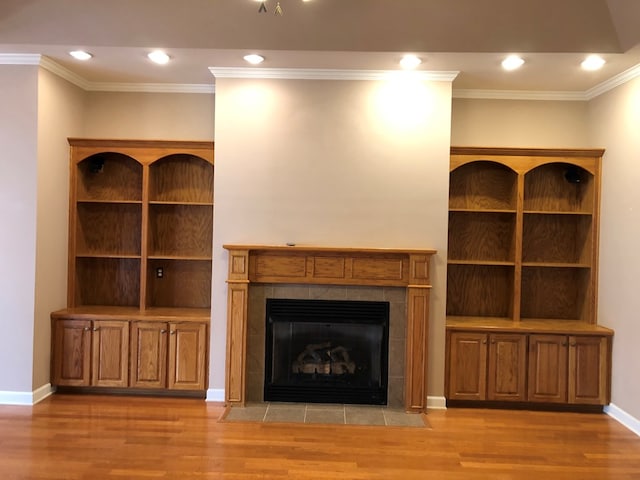 unfurnished living room with light hardwood / wood-style floors, ornamental molding, and a tile fireplace