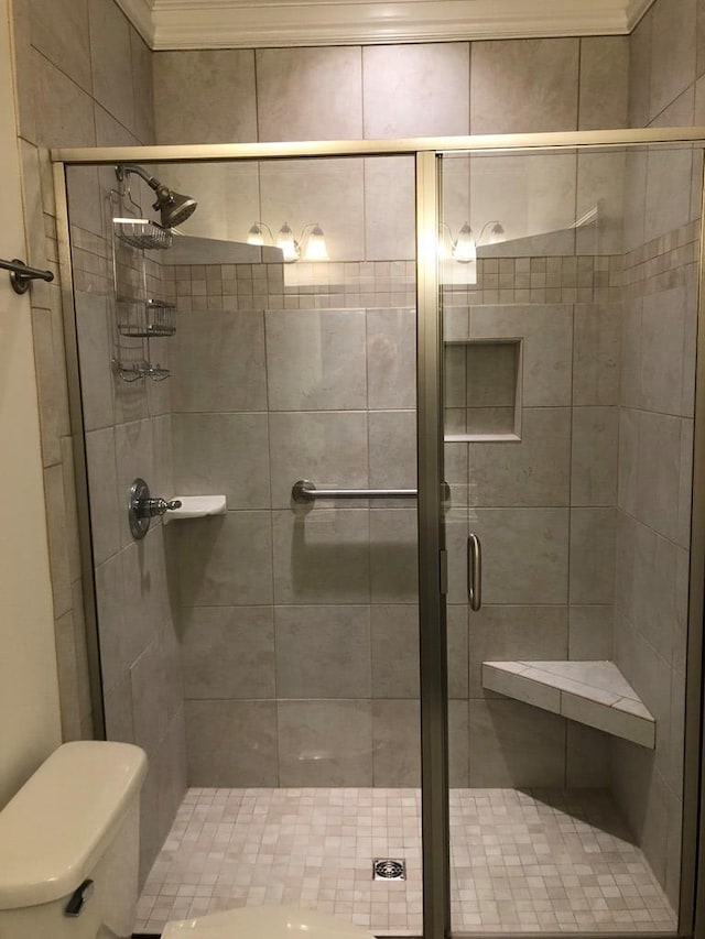 bathroom with toilet, walk in shower, and ornamental molding