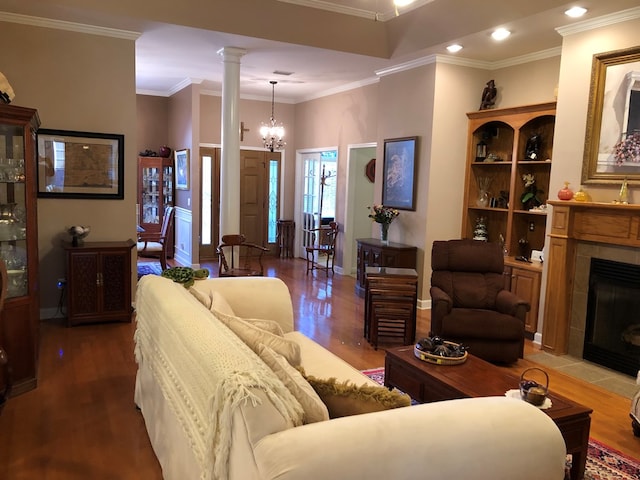 living room featuring ornamental molding, a fireplace, a notable chandelier, wood-type flooring, and decorative columns