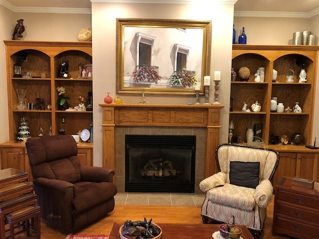 sitting room featuring light hardwood / wood-style floors, ornamental molding, and a tile fireplace