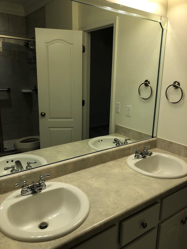 bathroom featuring a tile shower, vanity, and toilet