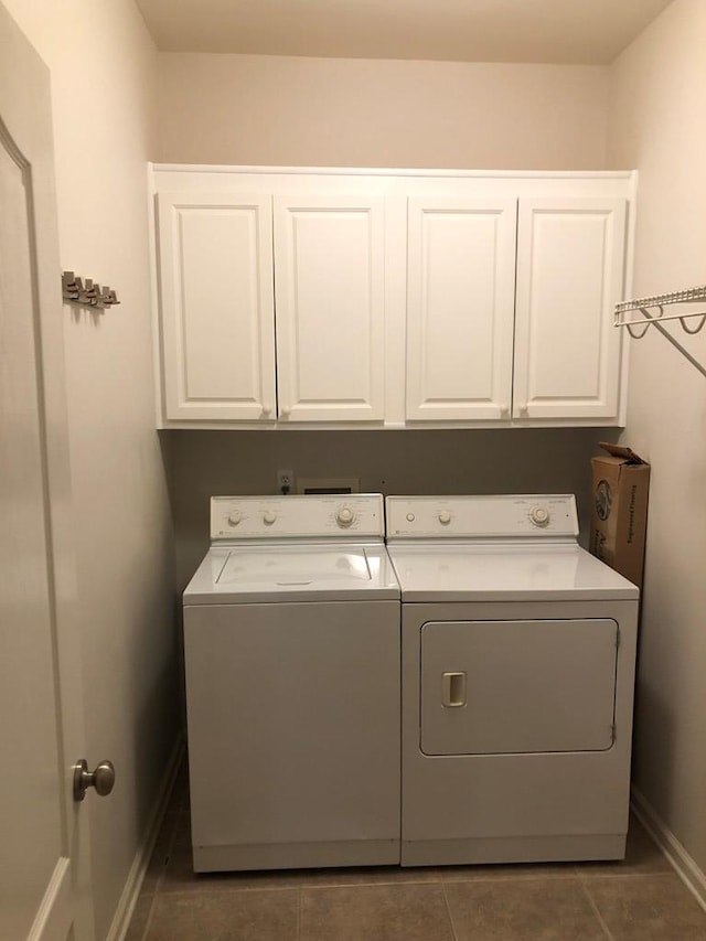 laundry room with washer and dryer, dark tile patterned floors, and cabinets