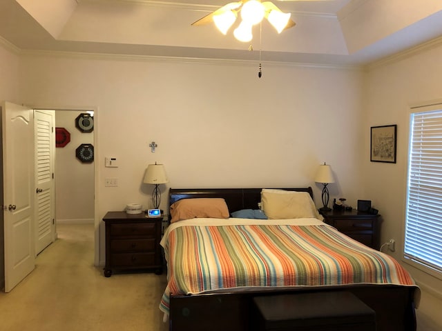 carpeted bedroom with ceiling fan, a closet, ornamental molding, and a tray ceiling