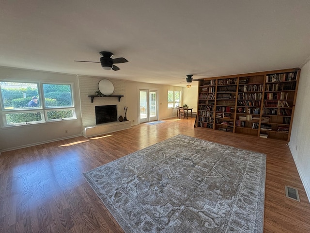 unfurnished living room with a fireplace, wood-type flooring, and a wealth of natural light