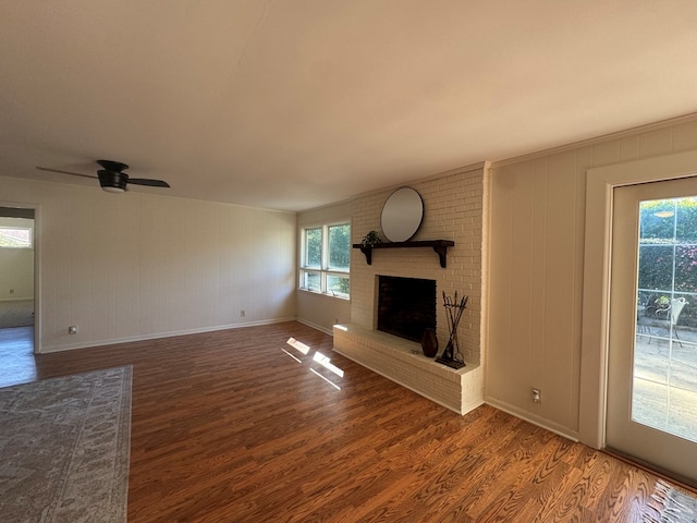 unfurnished living room with dark hardwood / wood-style floors, a brick fireplace, and ceiling fan