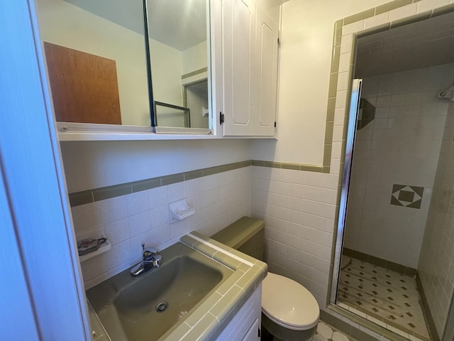 bathroom featuring vanity, a shower with shower door, tile walls, and toilet