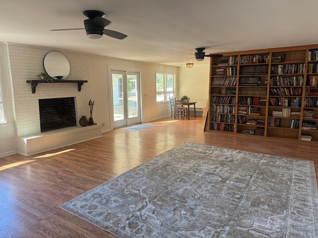 sitting room with hardwood / wood-style flooring, a brick fireplace, and ceiling fan