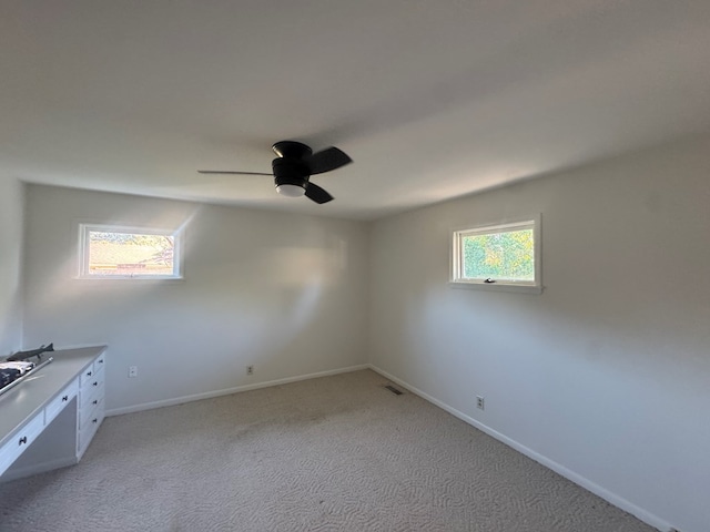 unfurnished room featuring ceiling fan, plenty of natural light, and light colored carpet