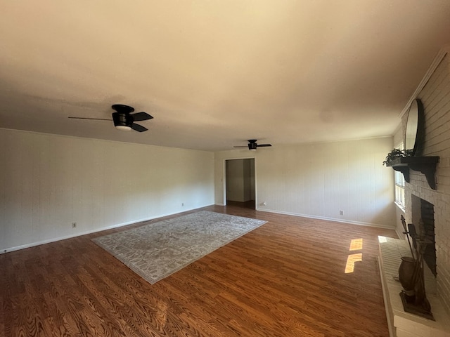 unfurnished living room featuring hardwood / wood-style floors, ceiling fan, and a brick fireplace