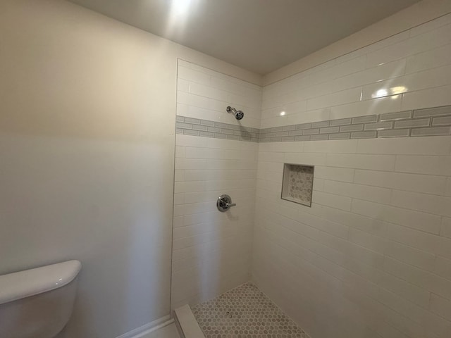 bathroom with a tile shower and toilet