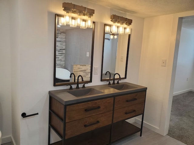 bathroom with a washtub, vanity, and a textured ceiling