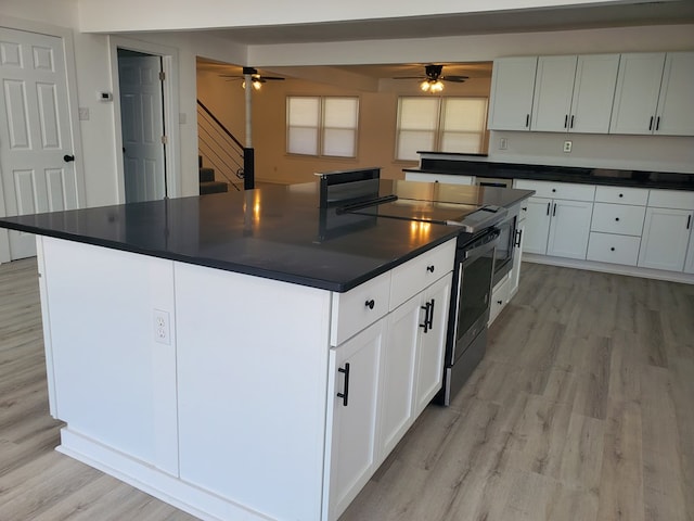 kitchen with stainless steel electric range, light hardwood / wood-style flooring, ceiling fan, a kitchen island, and white cabinetry