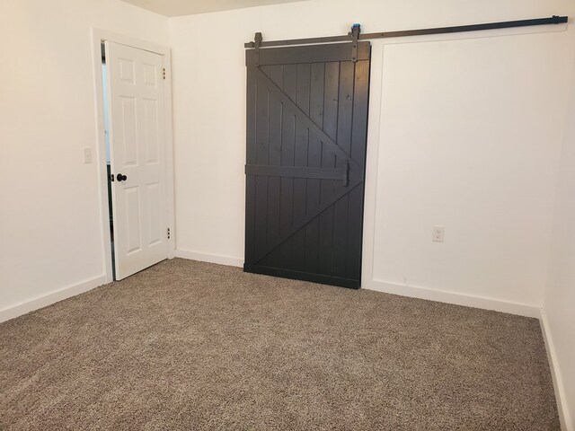 carpeted empty room with a barn door