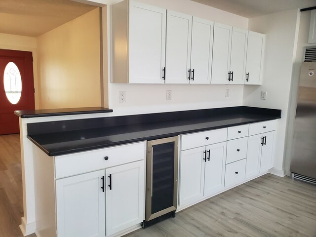 kitchen featuring high end refrigerator, light wood-type flooring, white cabinetry, and wine cooler