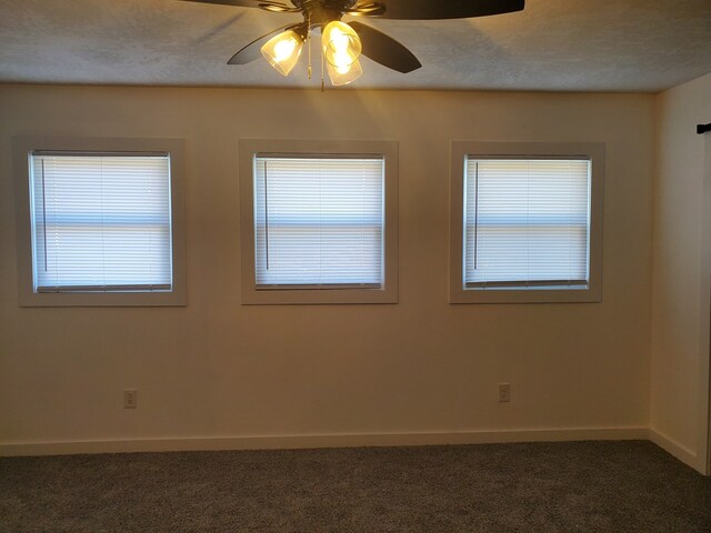 unfurnished room featuring dark colored carpet, ceiling fan, and a textured ceiling