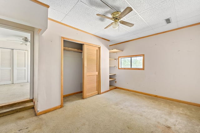 unfurnished bedroom with carpet flooring, a paneled ceiling, and ceiling fan