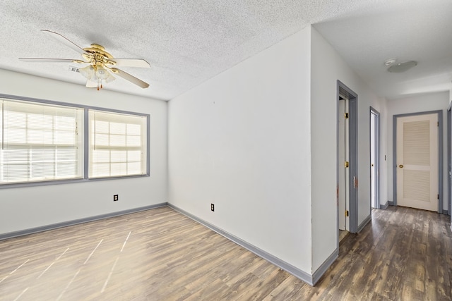 empty room featuring dark wood-type flooring, ceiling fan, and a textured ceiling