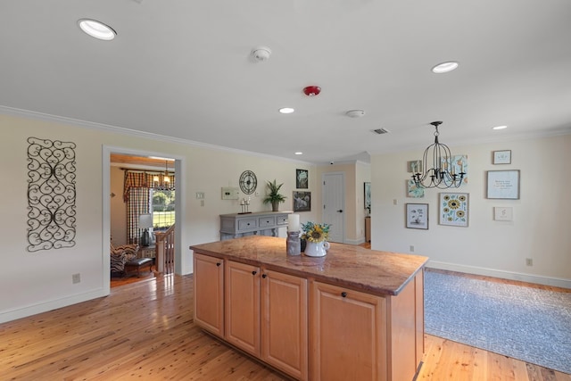 kitchen featuring a center island, light stone counters, crown molding, and light hardwood / wood-style flooring