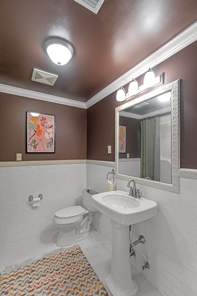 bathroom featuring tile patterned floors, toilet, tile walls, and crown molding