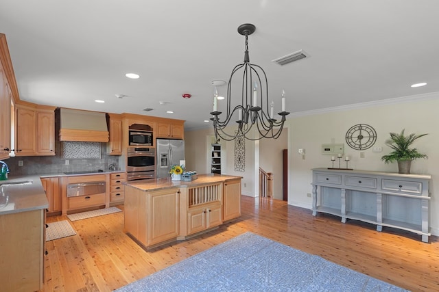 kitchen with sink, a kitchen island, appliances with stainless steel finishes, light hardwood / wood-style floors, and custom range hood