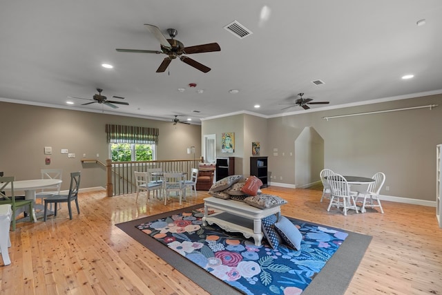 living room with light wood-type flooring, ceiling fan, and ornamental molding