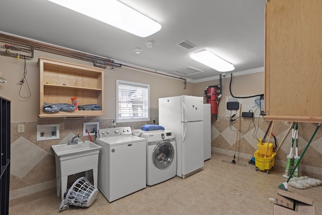 washroom with crown molding, sink, tile walls, and independent washer and dryer