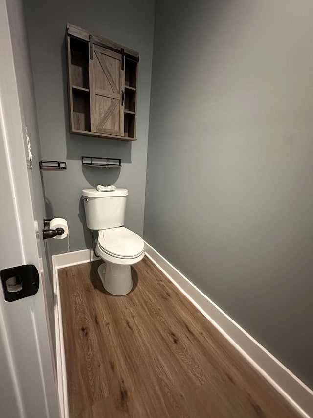 bathroom featuring toilet, baseboards, and wood finished floors