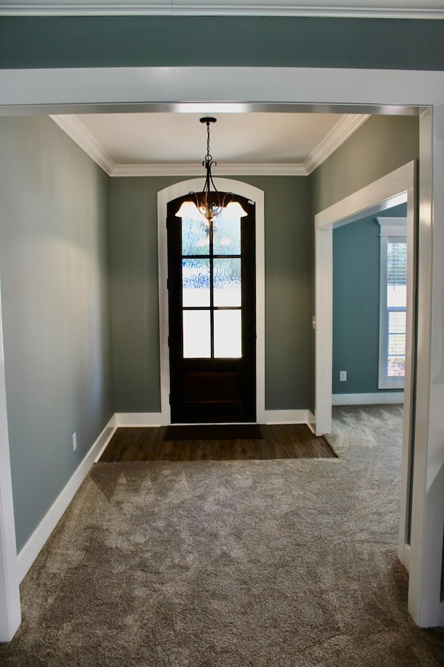 carpeted foyer featuring a notable chandelier, crown molding, and baseboards