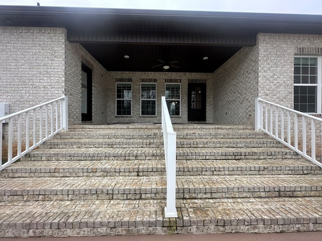 view of exterior entry featuring brick siding and ceiling fan