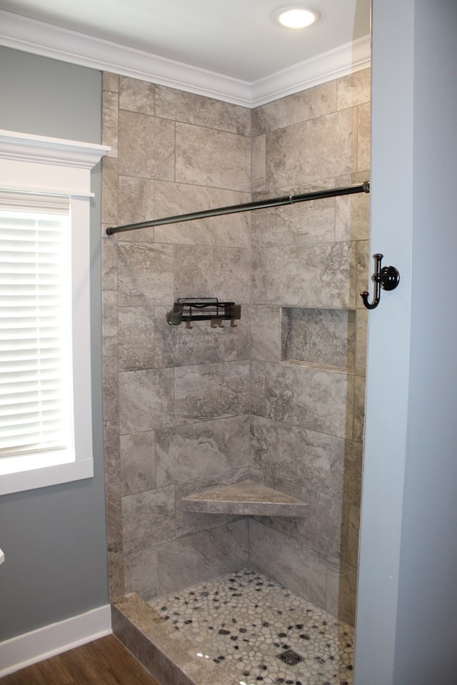 bathroom featuring crown molding, wood finished floors, baseboards, and tiled shower