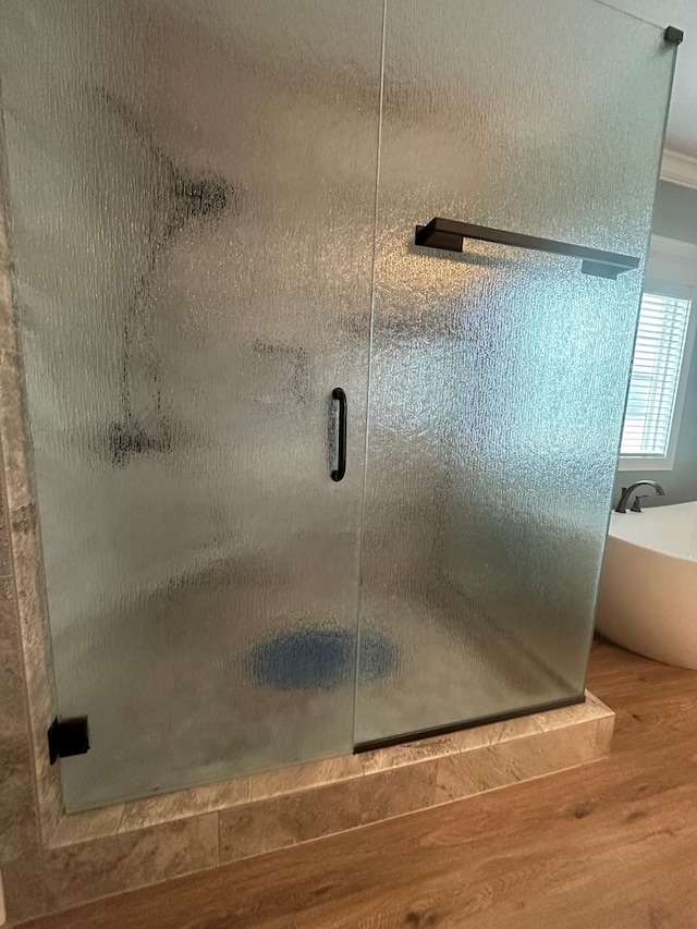 bathroom featuring a soaking tub, wood finished floors, and a shower stall