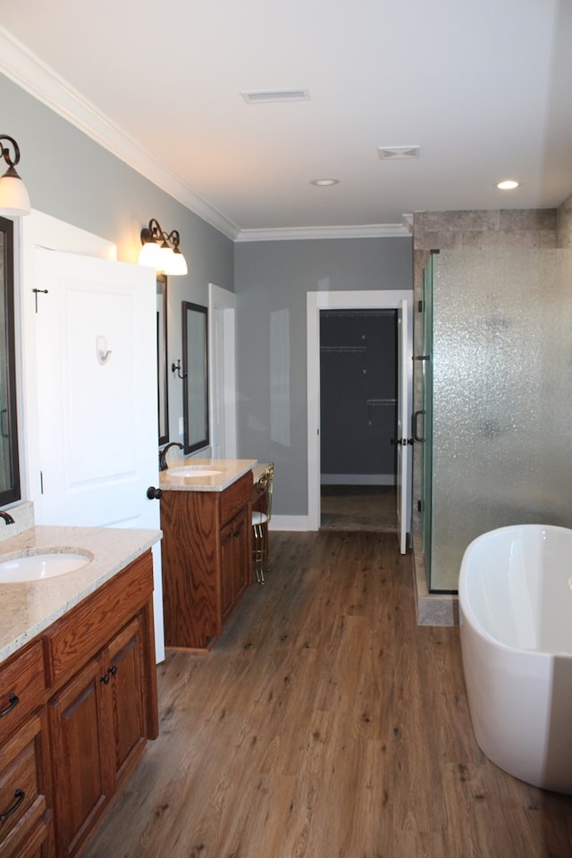 bathroom with a sink, visible vents, wood finished floors, and a shower stall