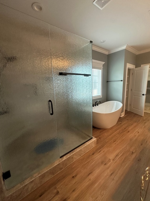 bathroom featuring visible vents, a stall shower, ornamental molding, wood finished floors, and a soaking tub