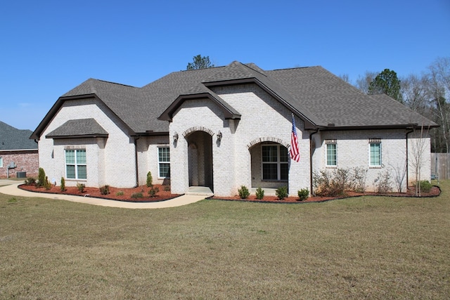 french country home with a front yard and brick siding