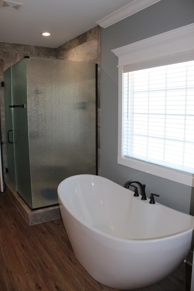 full bath featuring visible vents, ornamental molding, wood finished floors, a shower stall, and a soaking tub