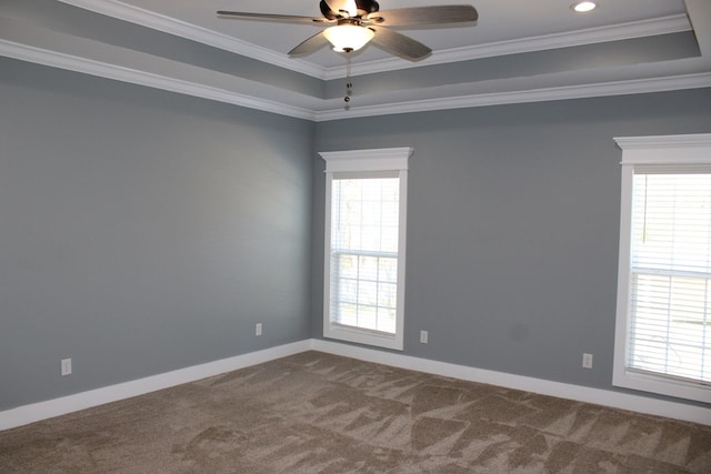 unfurnished room with baseboards, a tray ceiling, ornamental molding, a ceiling fan, and dark colored carpet