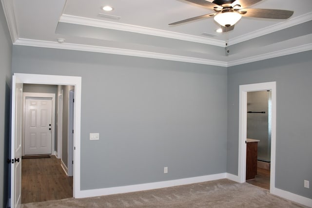 unfurnished bedroom with a tray ceiling, recessed lighting, carpet, crown molding, and baseboards