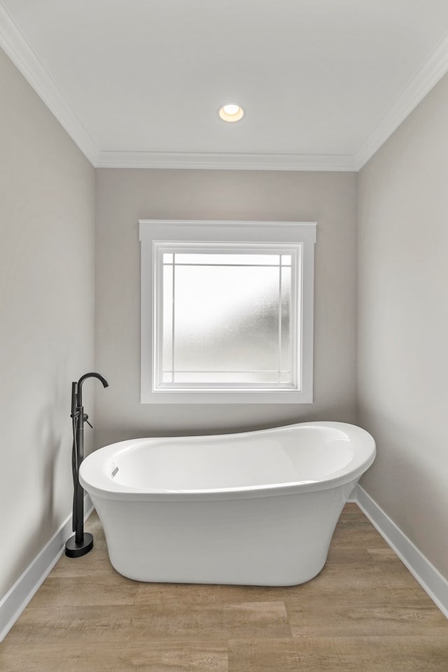 full bathroom with a freestanding tub, wood finished floors, and baseboards